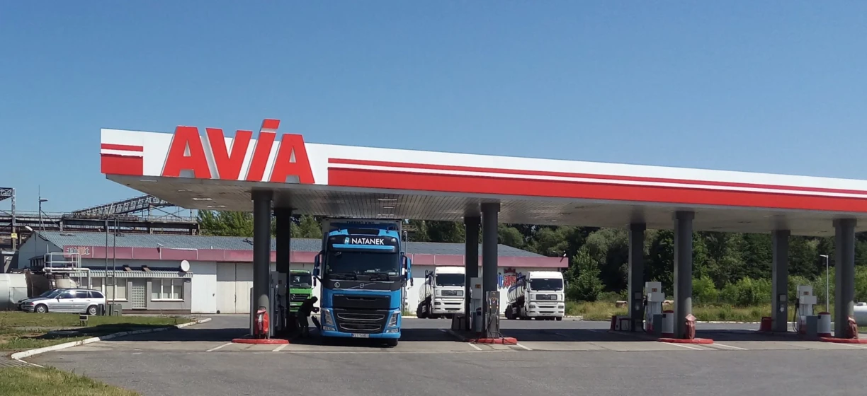 A commercial truck filling up at a gas station with a NATANEK fuel dispenser on a highway. Gasoline being pumped into the vehicle.